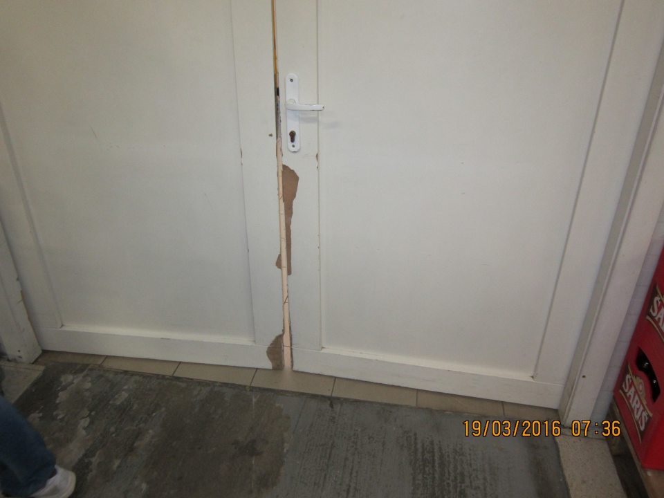 Poškodené dvere spájajúce sklad s predajnou plochou.