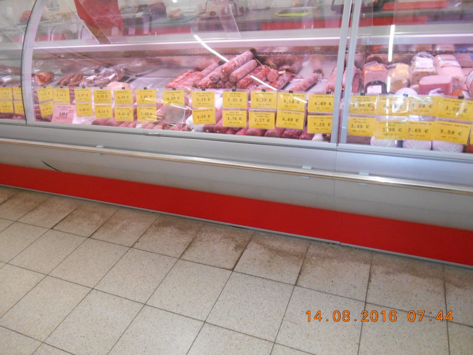 V predajni pred chladiacim pultom s mäsovými výrobkami znečistená podlaha.