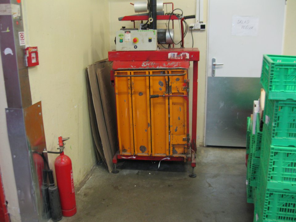 V prevádzke znečistená stena a podlaha v tesnej blízkosti umiestnenia lisovacieho zariadenia na kartóny.