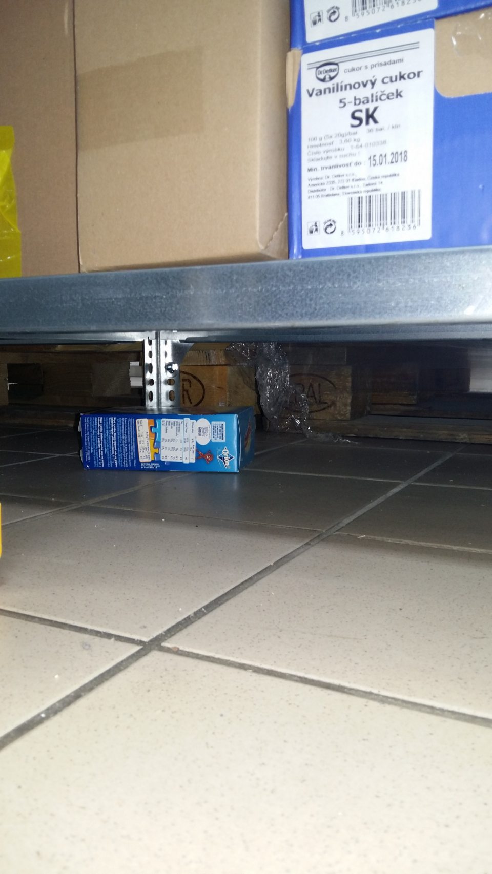 Popadaný tovar pod regálmi v sklade.