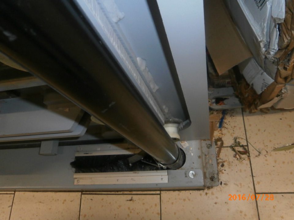 V sklade prevádzky znečistená podlaha v okolí kovových zábran a lisu na kartónové obaly 