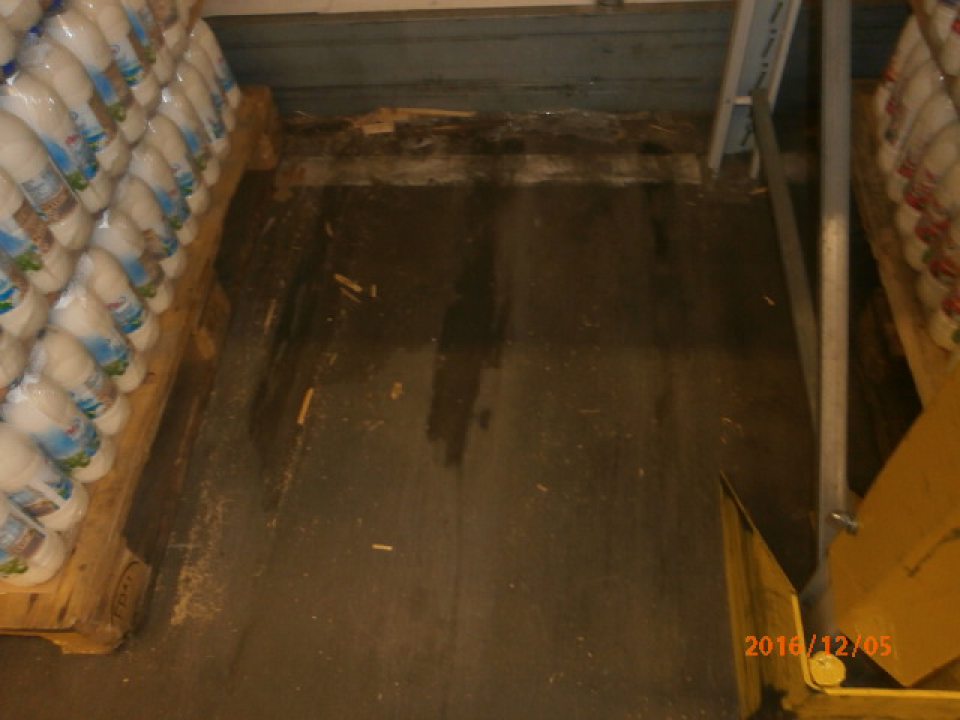 V sklade prevádzky znečistená podlaha za paletami s čerstvým mliekom.