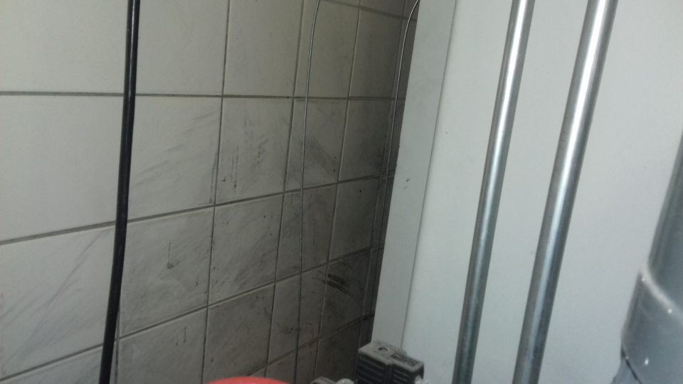 Znečistený obklad steny za lisom na kartónové obaly v sklade potravín