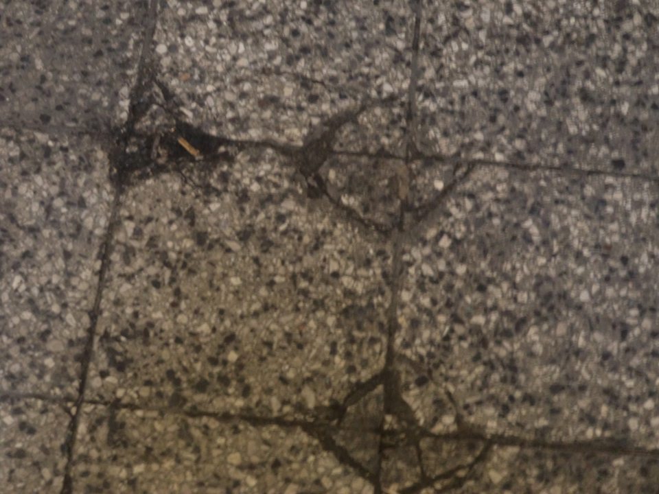 Poškodená, popraskaná a vypadaná dlažba v sklade potravín