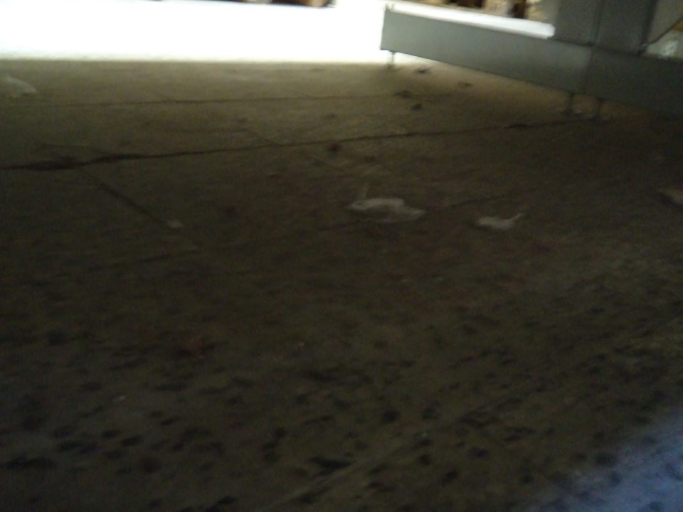 Znečistená,zaprášená podlaha pod regálom s čokoládami a keksami v sklade potravín