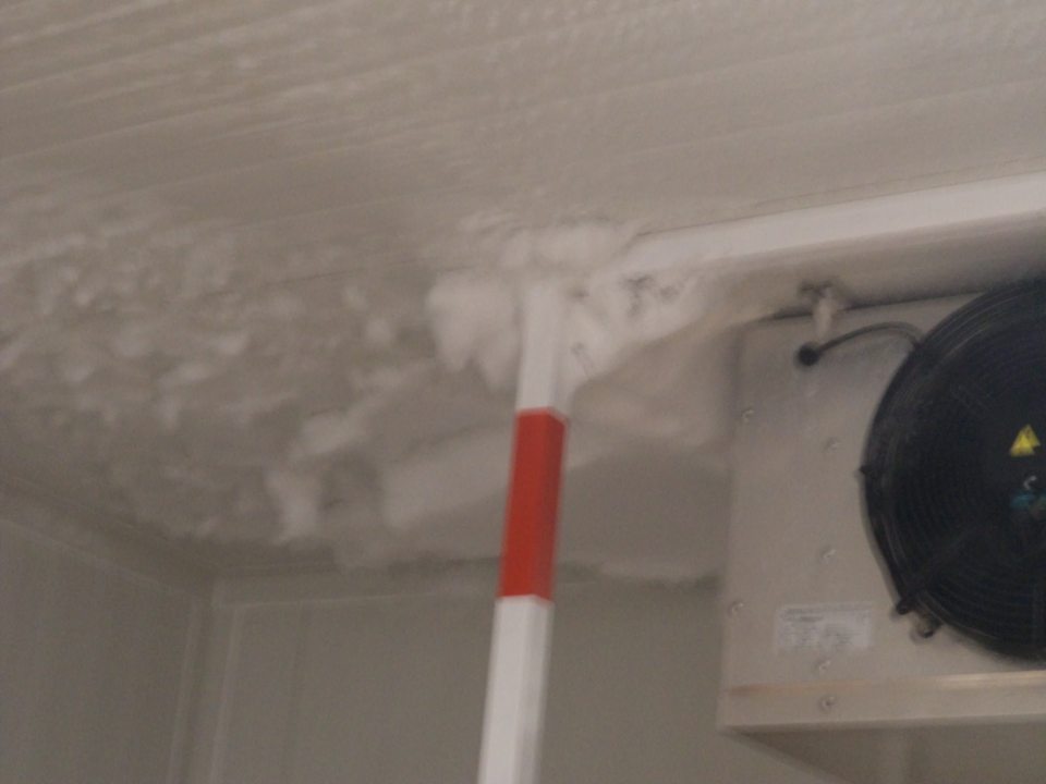 Hrubé vrstvy námrazy na strope okolo chladiacej jednotky  mraziaceho boxu na mrazené pekárske polotovary