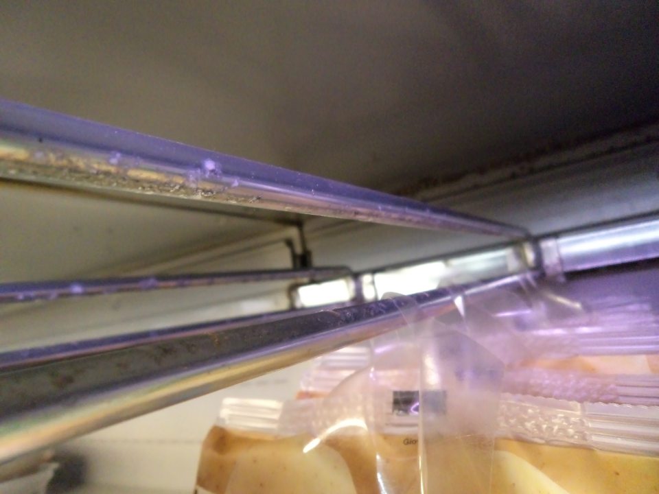 Znečistená zadná stena a závesný mechanizmus chladiacej vitríny na hotové jedlá a originálne balené zeleninové šaláty