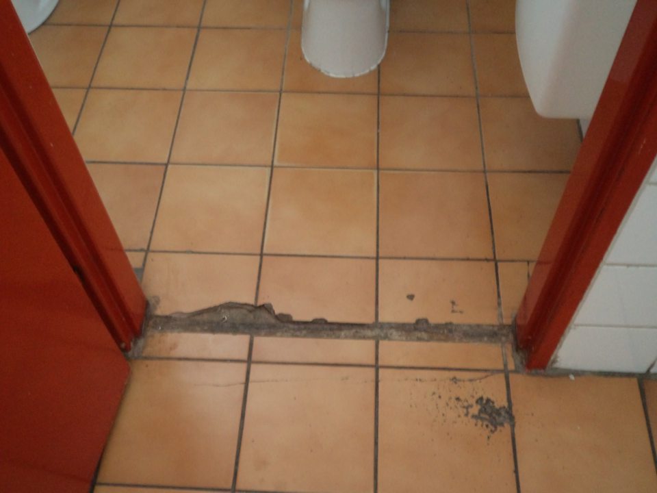 Poškodená podlaha pri vstupe do WC v ženskej šatni