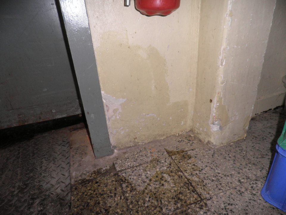 Poškodený povrch steny pri príjmových dverách.