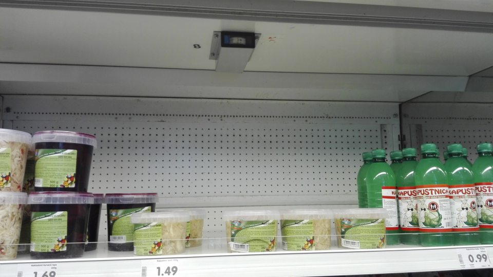 Znečistená zadná stena chladiaceho zariadenia s ponukou baleného kapustového šalátu.