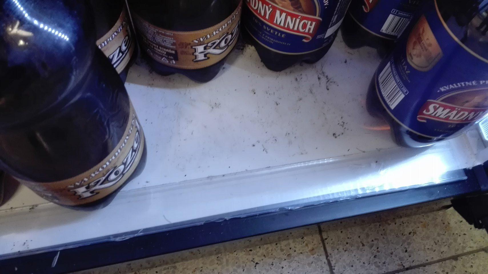 Znečistené dno chladiacej vitríny s ponukou piva.