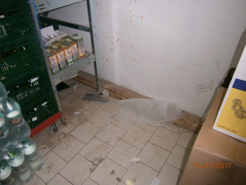 Znečistená podlaha a opotrebovaný povrch steny v sklade alkoholu a tovaru neurčeného na predaj.