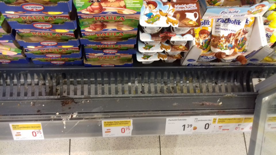 V chladiacich vitrínach mliečnych výrobkov znečistené mriežky, priestor pod mriežkami zatečený zbytkami potravín.