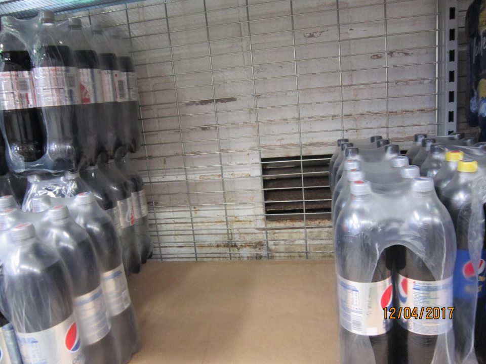 Znečistená a zaprášená stena za regálom s nápojmi. 