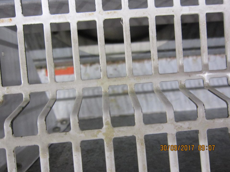 Regál na predajnej ploche znečistený zbytkami potravín, kúskami paperikov a kartónov a zhlukom prachu.