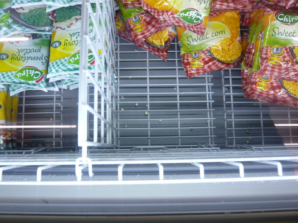 V predajni znečistené dno mraziarenského boxu zvyškami mrazenej zeleniny.