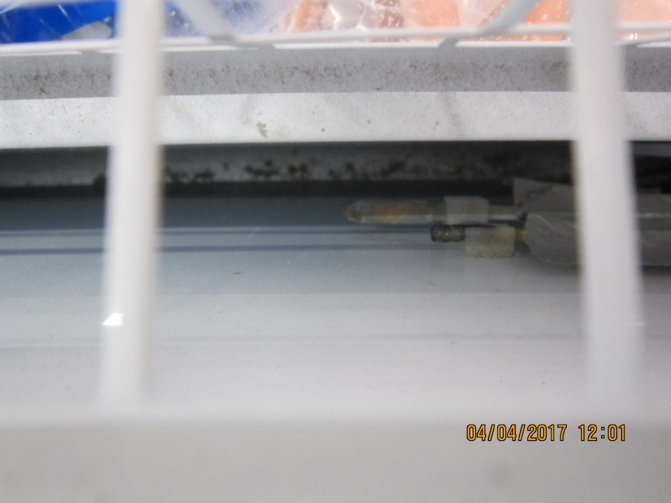 Znečistené dno mraziarenskej vitríny s mrazenými rybami na predajnej ploche.