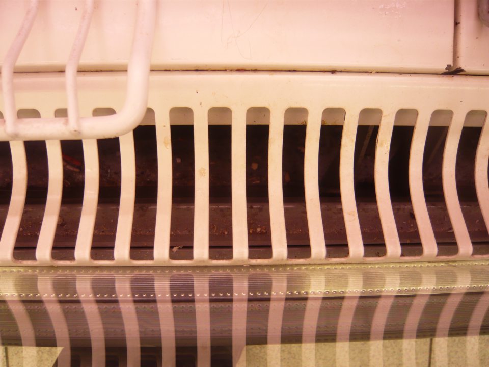 Znečistené dno pod mriežkou v chladiarenskej vitríne s chladeným mäsom a mäsovými výrobkami.