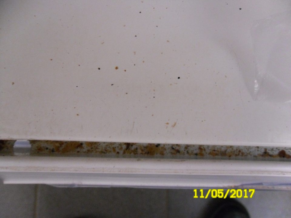 V predajni znečistený regál medzi lištou s cenovkami a úložnou plochou s pekárskymi výrobkami.