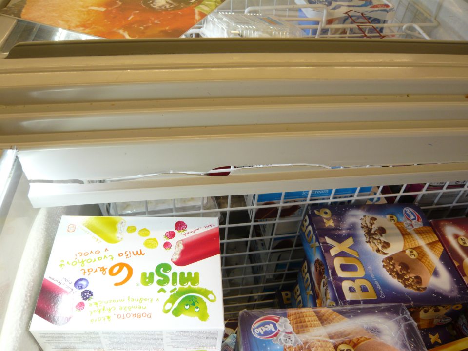 Poškodená plastová obvodová lišta pod posuvnými dvierkami v mraziarenskej vitríne.