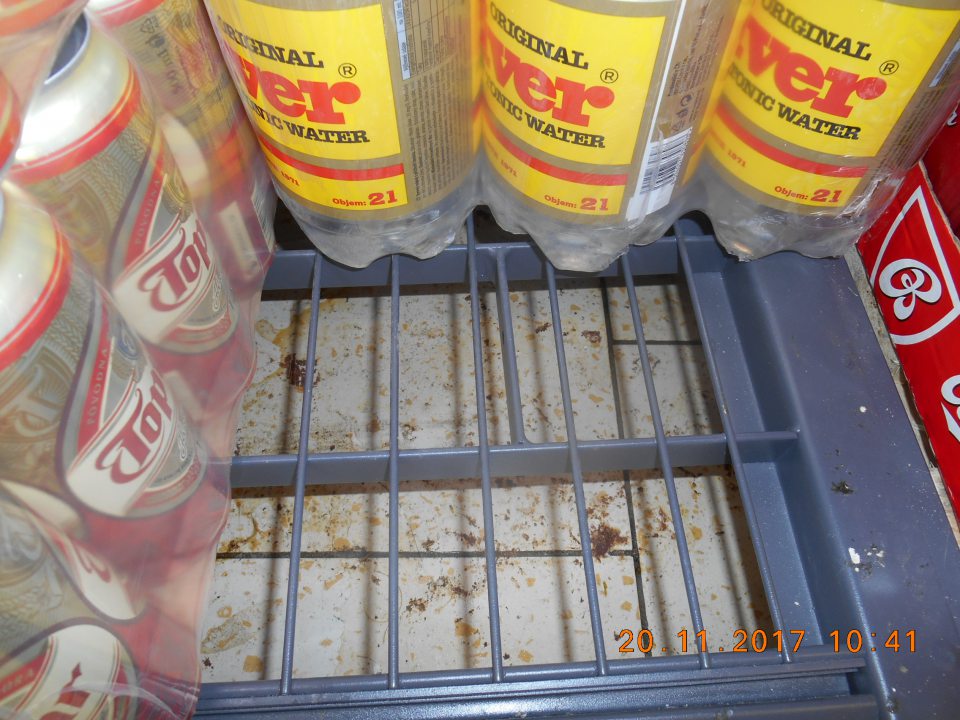 Na predajnej ploche zaschnuté hrubé nečistoty pod regálom na uchovávanie alko a nealko nápojov.