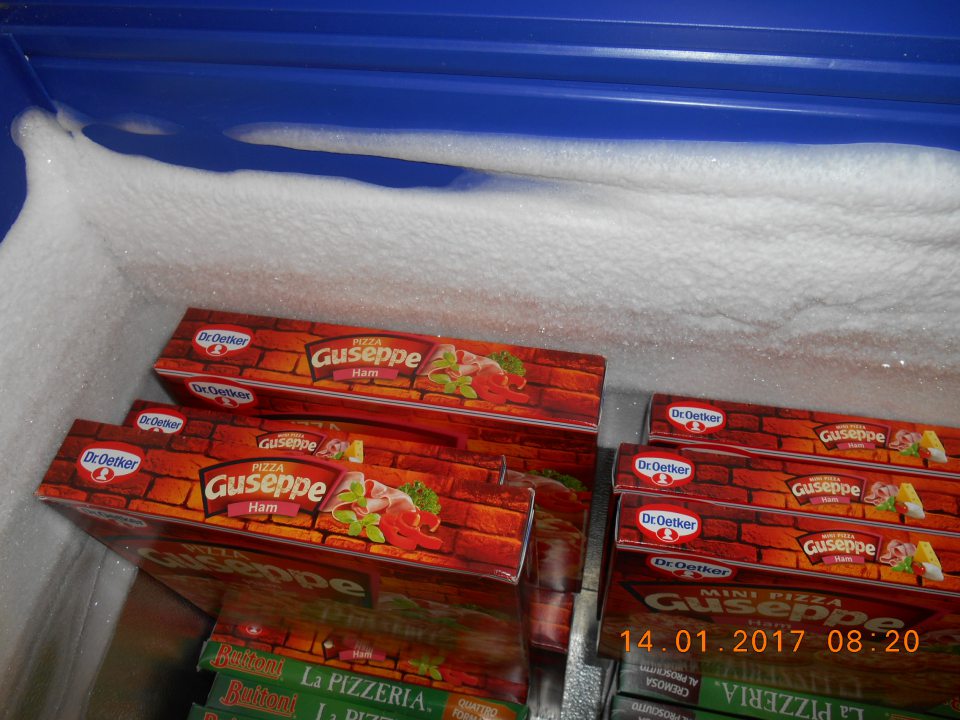 Silná námraza na stenách mraziarenského zariadenia na uchovávanie hlbokozmrazenej pizze.