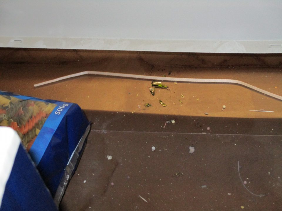 V regály s predávanými cestovinami rozsypané potraviny, úlomky skla, nečistoty.