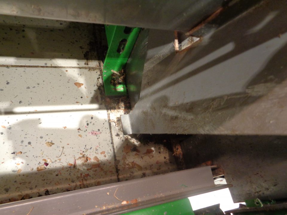 Priestor v dolnej časti chladiaceho zariadenia s kvasenou kapustou a šampiňónmi znečistený prachom, zastaranou špinou, zvyškami uložených potravín a zaschnutými škvrnami po vytečenej tekutine.