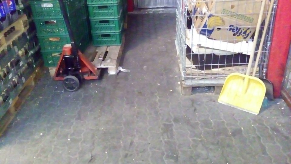 V priestore vonkajšieho skladu podlaha na ťažšie dostupných miestach znečistená prachom, manipulačnou nečistotou a zvyškami obalového materiálu.