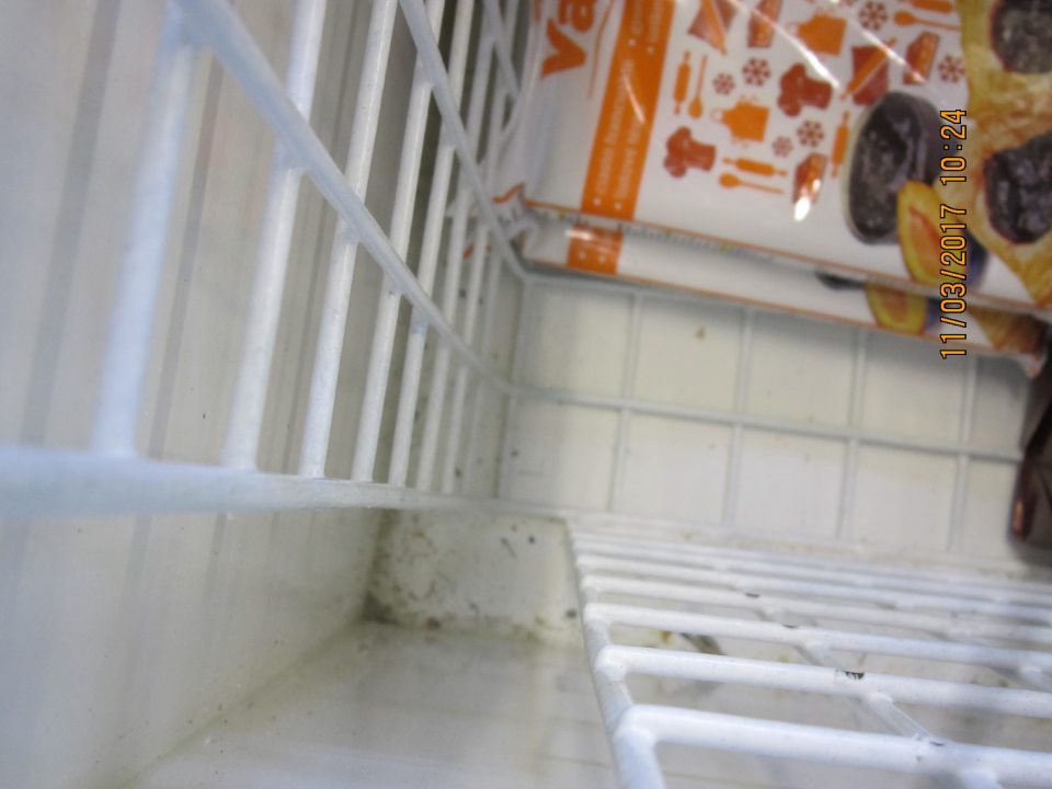 Dno mraziaceho zariadenia na predajnej ploche znečistené drobnými nečistotami z kartónových obalov.