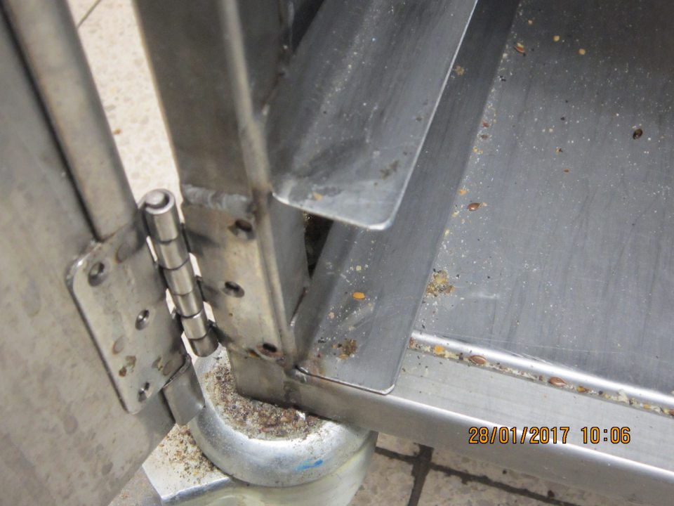 V prevádzke kovový pekárenský vozík znečistený omrvinkami a drobnými nečistotami.