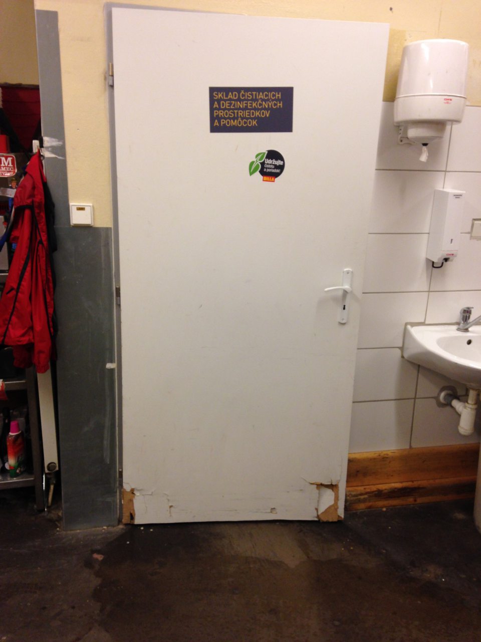 Poškodený povrch dverí skladu čistiacich a dezinfekčných prostriedkov.