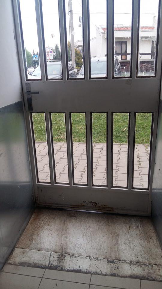Poškodená tesniaca lišta na vstupných dverách; poškodený náter dverí.