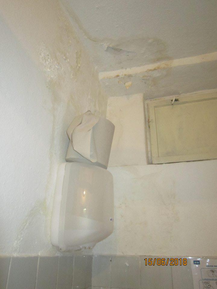 Stena vo WC poškodená s olupujúcou sa omietkou