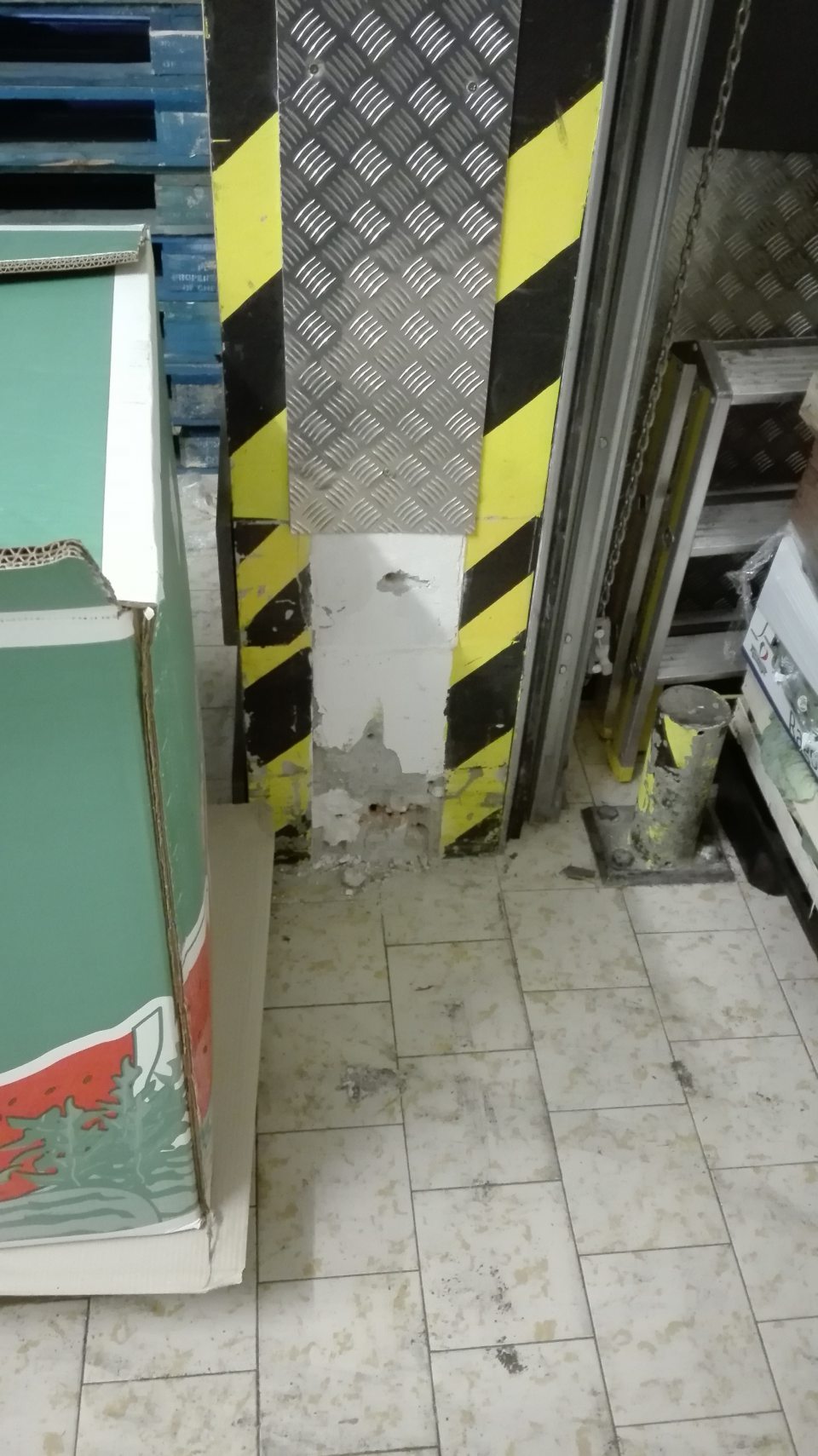 Poškodená stena pri rolovacej bráne v suchom sklade.