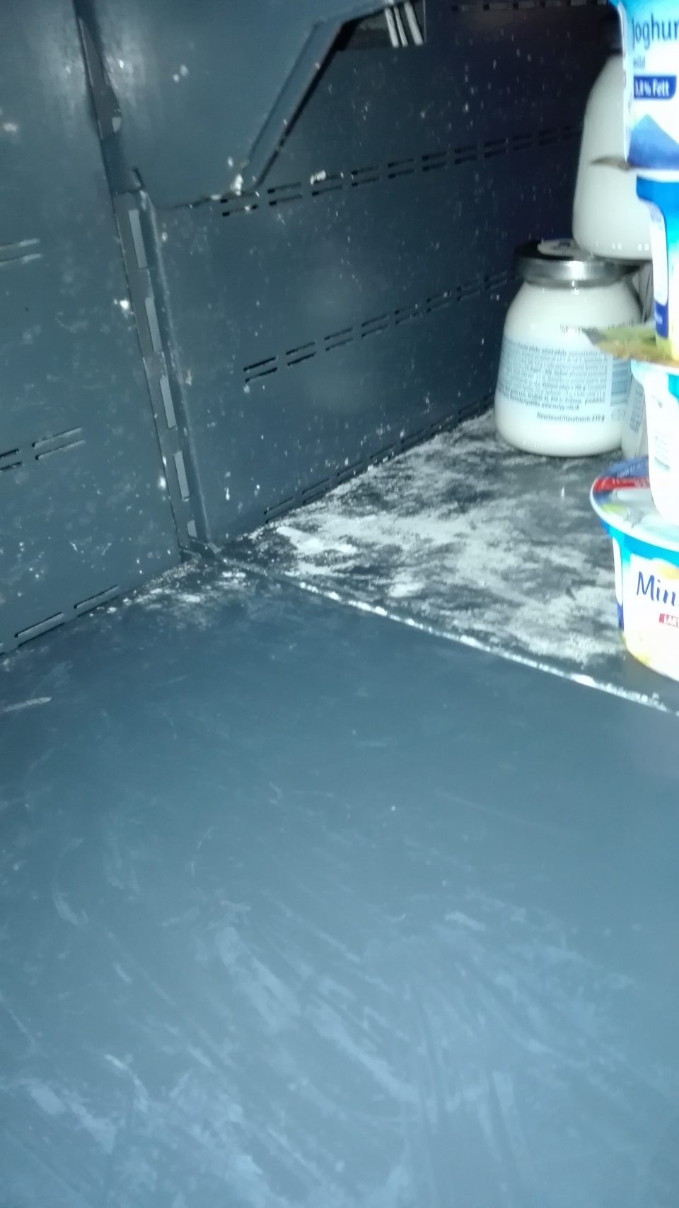 Znečistené police chladiacej vitríny s ponukou mliečnych výrobkov.