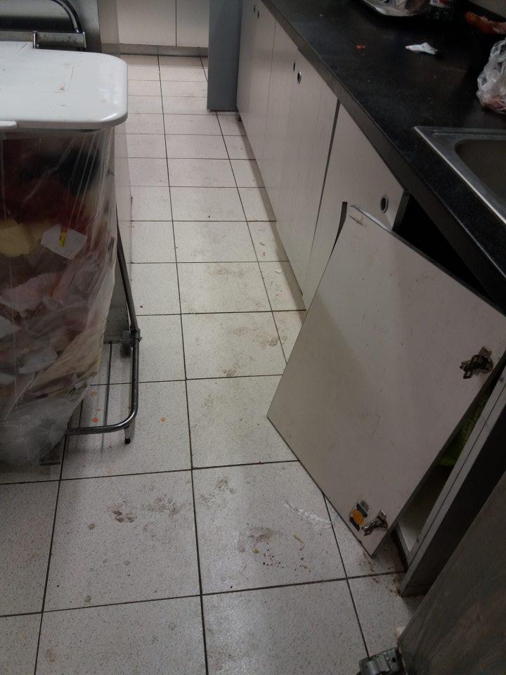 Znečistená podlaha a poškodené dvierka príručnej skrinky v prípravovni lahôdok.