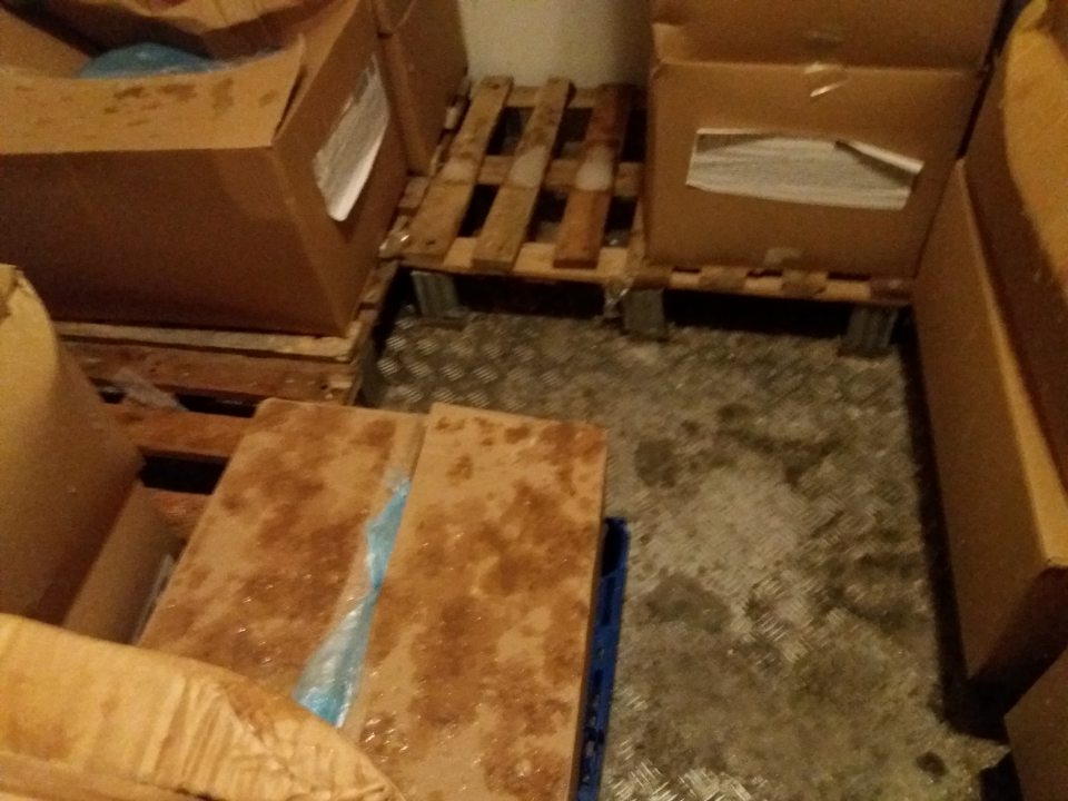 Namrznutý kondenzát na podlahe a krabiciach s tovarom v mraziacom sklade.