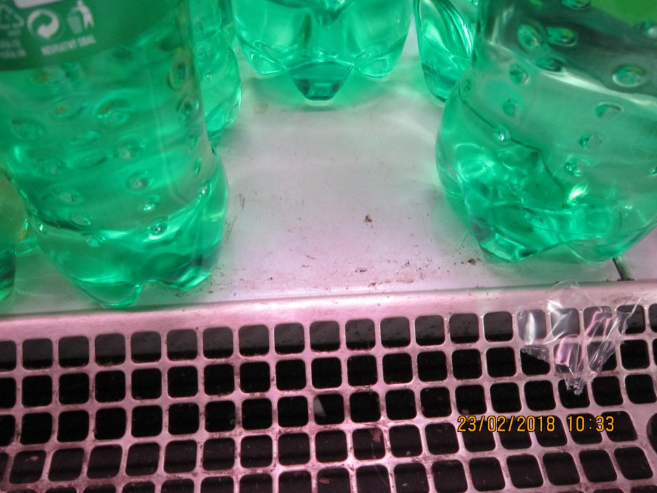 Pod mriežkami chladiacej vitríny nápojov sú nečistoty papieriy, zbytky potravín