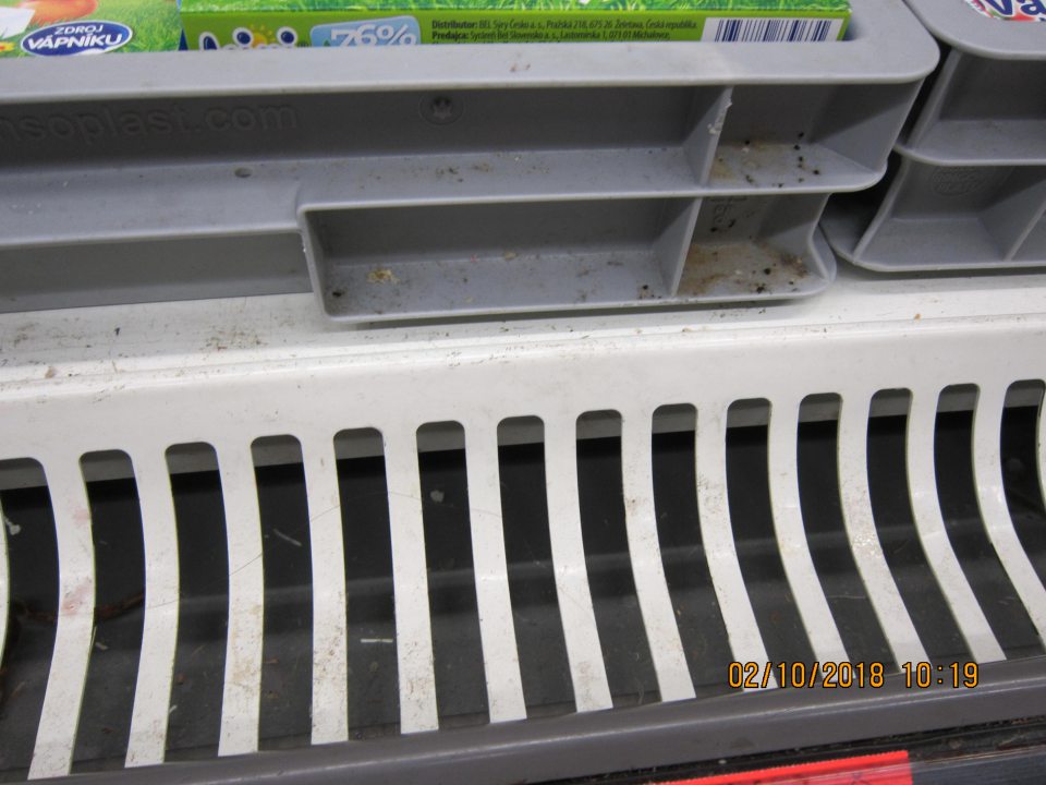 Znečistený regál  mliečnych výrobkov zaschnutými zbytkami potravín.