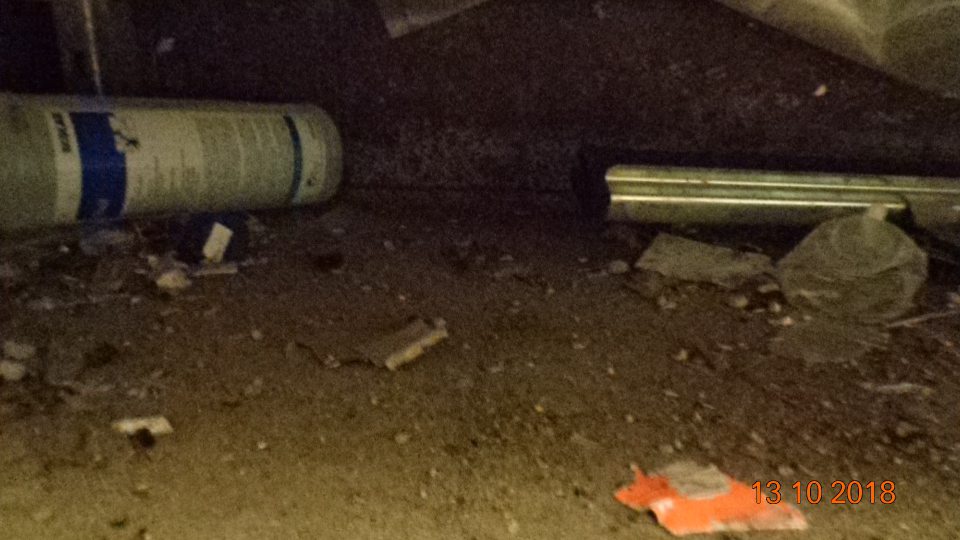 V čistiacej miestnosti  pod regálom hrubá vrstva prachu, fľaše rôzne zbytky potravín, plastov.