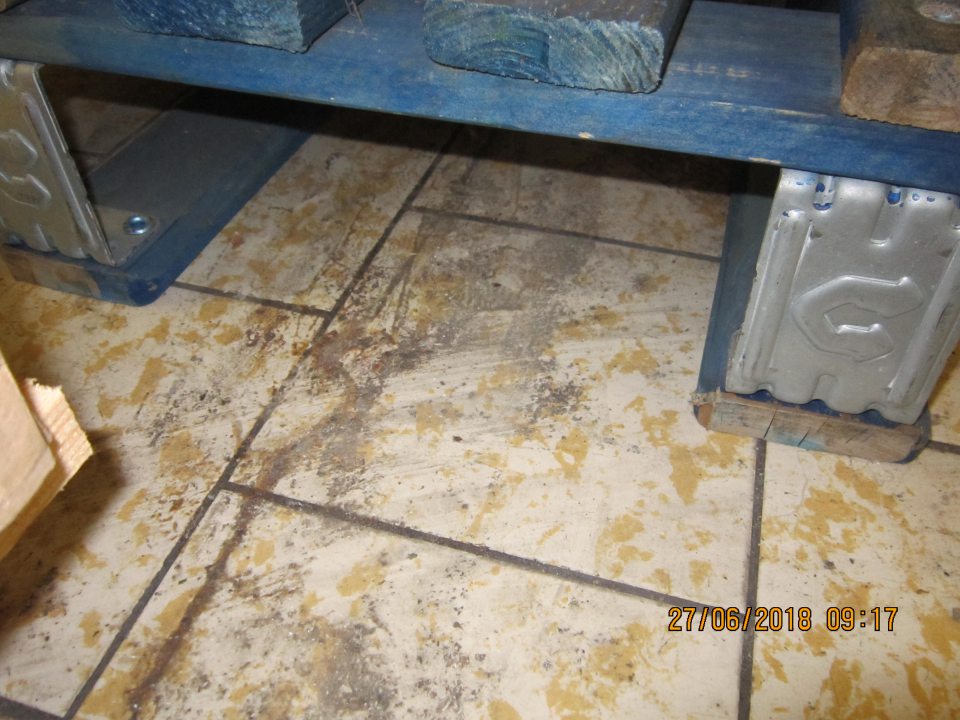 Pri paletách s tovarom znečistená podlaha čiernou zaschnutou špinou.