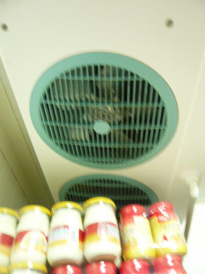 Znečistená klimatizačná jednotka v chladiarenskom boxe s uchovávanými mliečnymi výrobkami v sklade predajne.