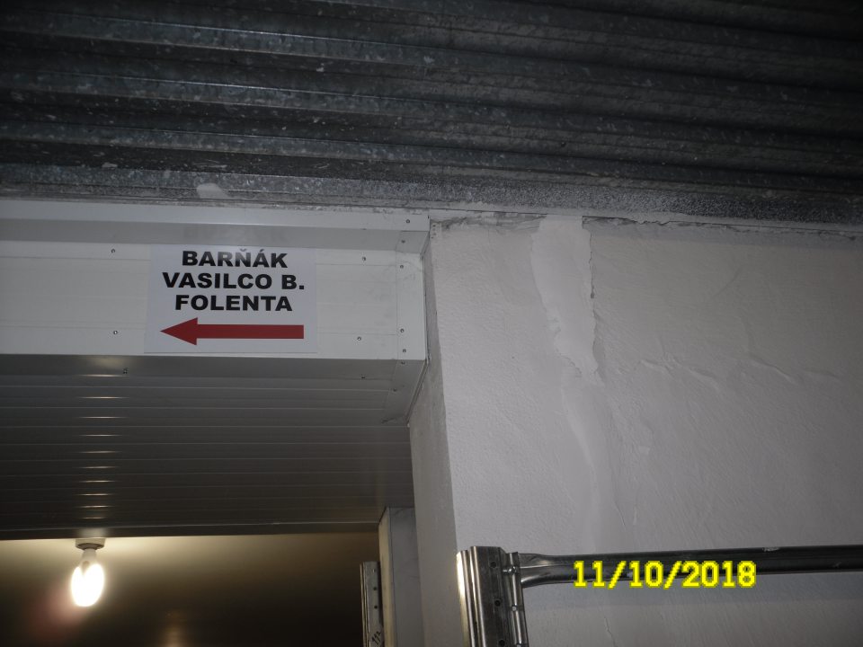 Poškodená, opadávajúca omietka nad regálmi s uloženými suchými potravinami.