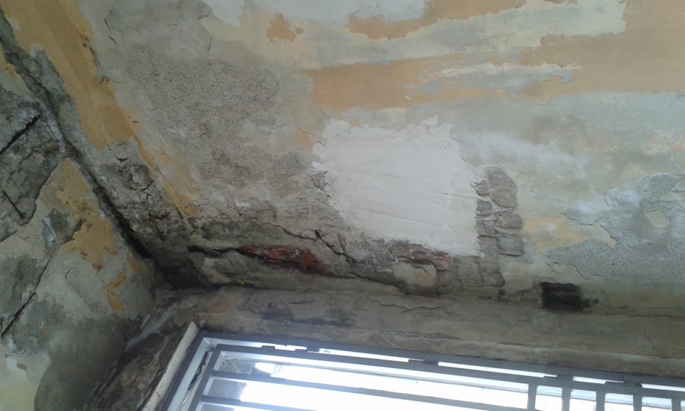 Poškodená omietka na stene a strope pri vstupe do prevádzkárne.