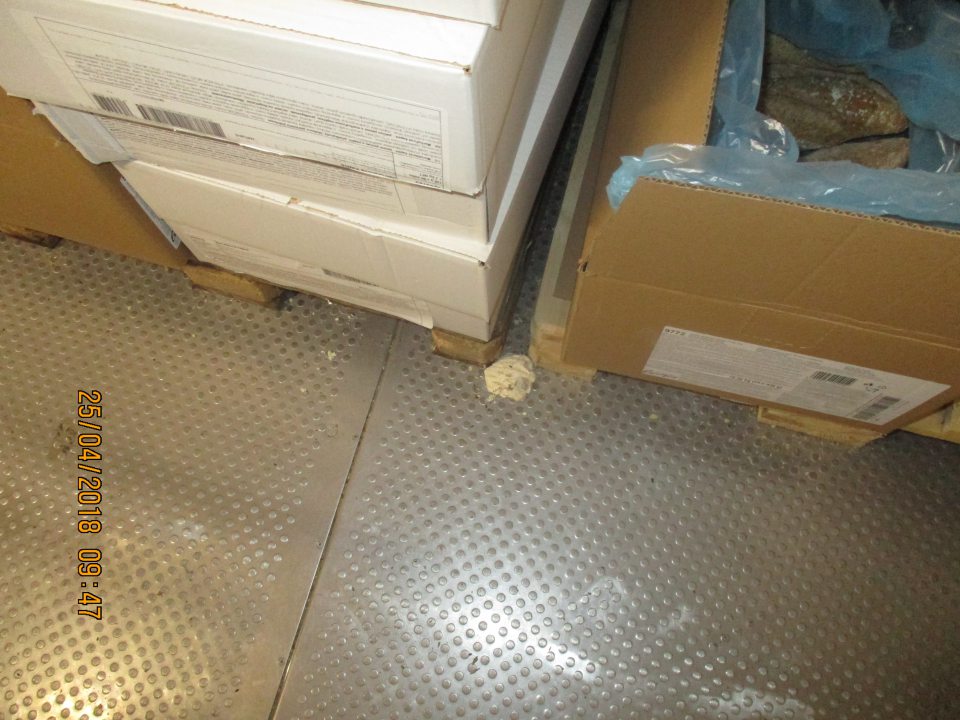 Znečistená podlaha so zvyškami obalového materiálu v mraziacom sklade.