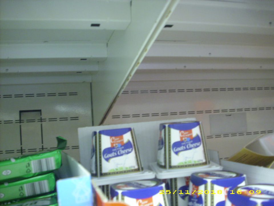 Chladiaca vitrína na uchovávanie mliečnych výrobkov na viacerých miestach skorodovaná s poškodeným hygienickým náterom.