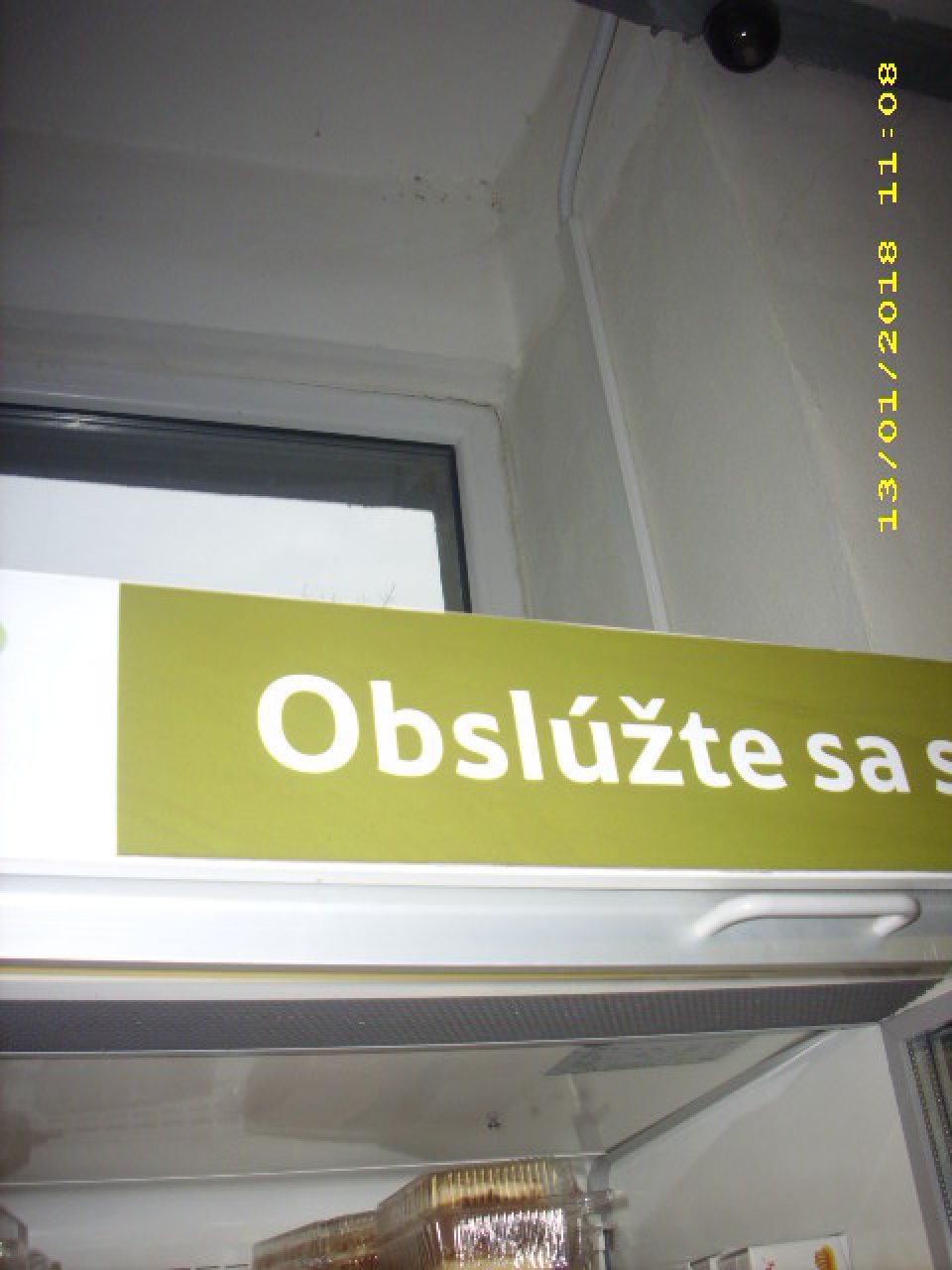 Nad regálom chladiacej vitríny s cukrárskymi výrobkami a bagetami výskyt pavučín, nečistôt a začínajúcej plesne v rohoch stien a stropu.