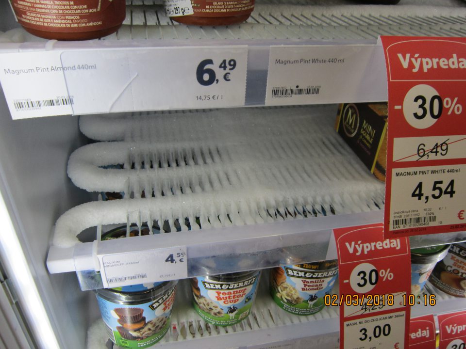 Silná námraza na mriežkach mraziarenského zariadenia na uchovávanie mrazených nanukov a krémov na predajnej ploche.