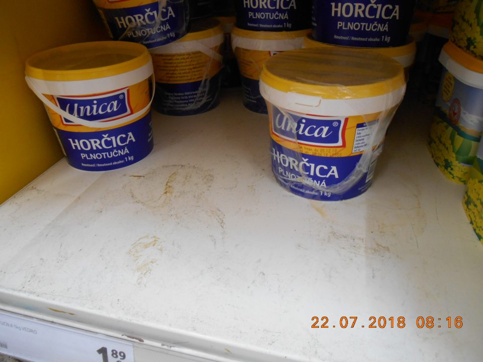 Nánosy prachu a zaschnutá špina na regáli na úseku predaja horčíc na predajnej ploche.